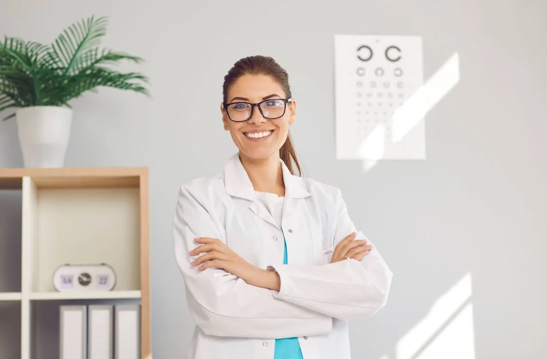 An eye-care provider in an exam room with a vision chart
