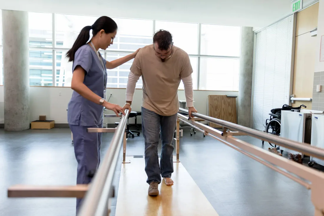 A physical therapist guiding a patient through gait training in a clinic